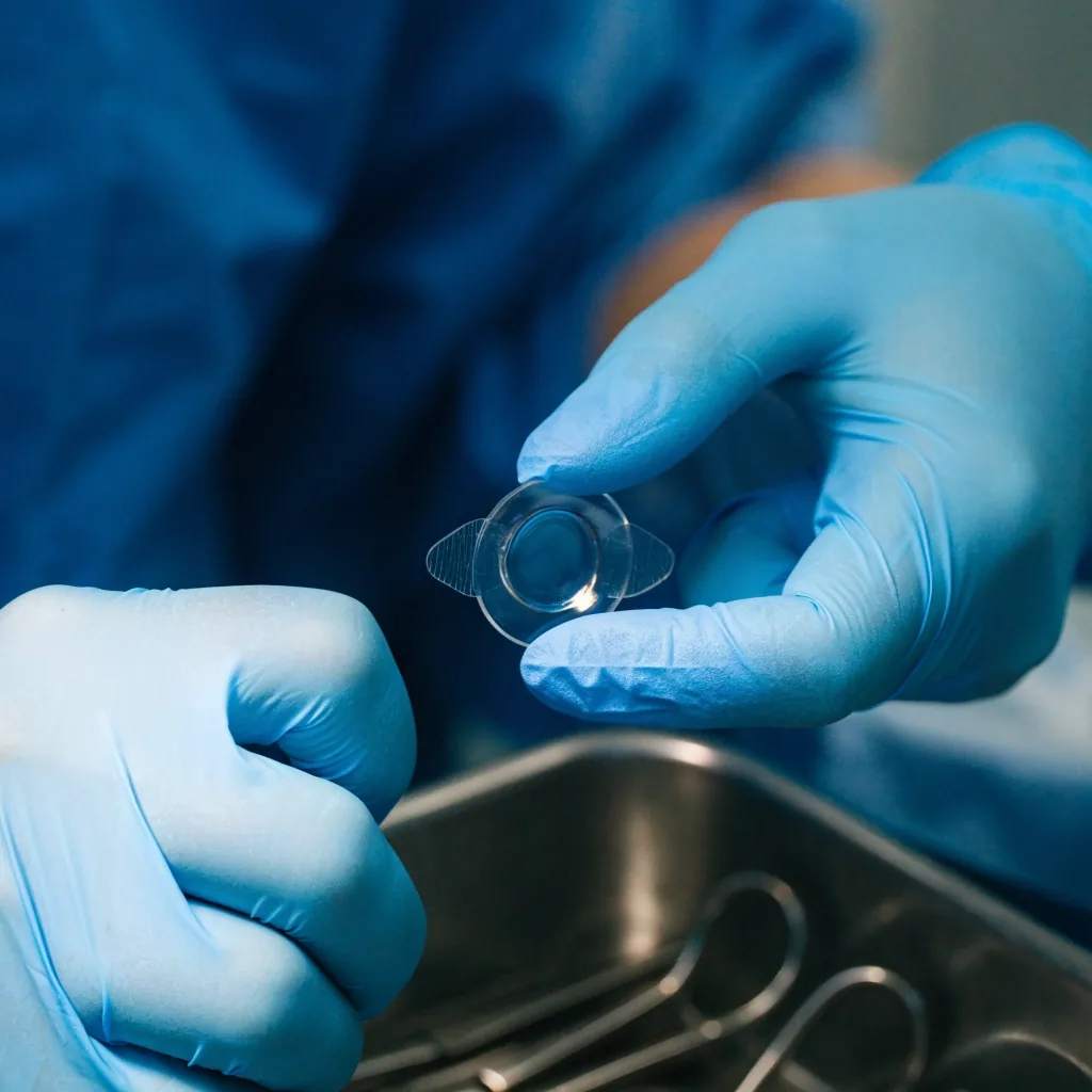 Ophthalmologist in a Jakarta operating room holding a replacement intraocular lens implant